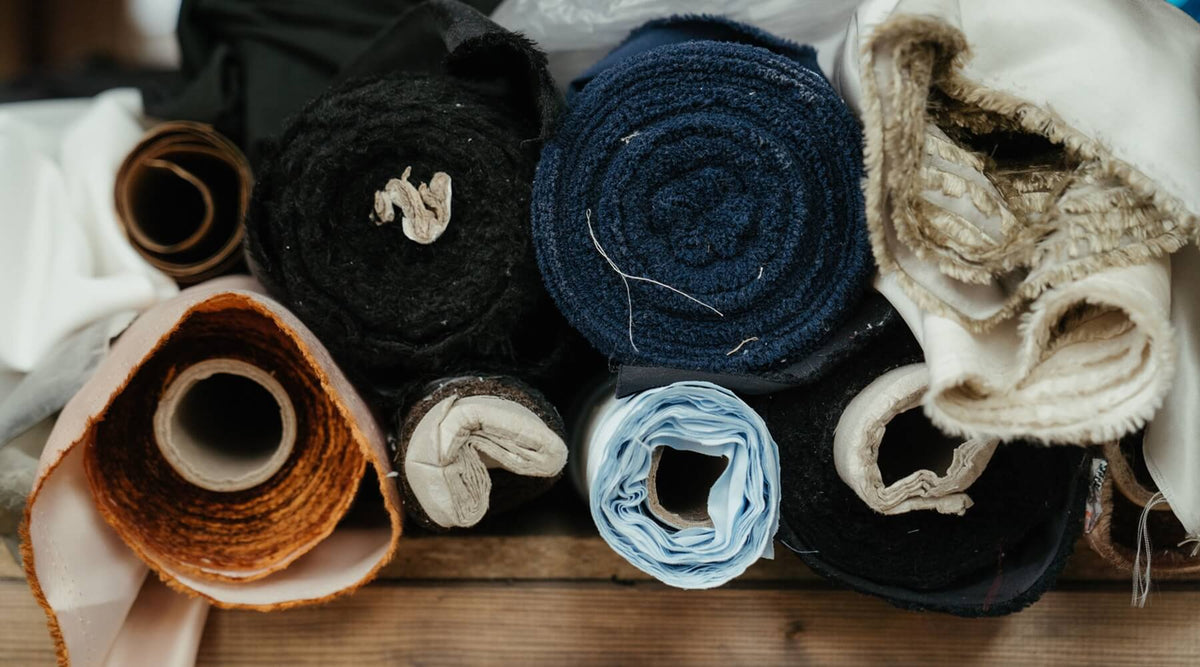 A close-up of various rolls of fabric in different textures, suggesting how certain couch fabrics attract cat scratching