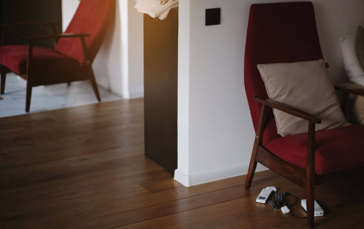 A living room with red armchairs, showing a common area where you might need to stop cats scratching wooden furniture legs