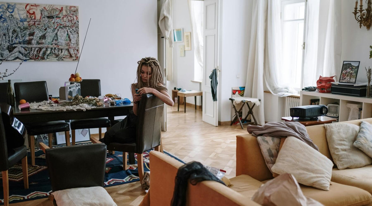 A person sits at a cluttered dining table in a minimalist home, illustrating the challenge to hide cat clutter in a minimalist home