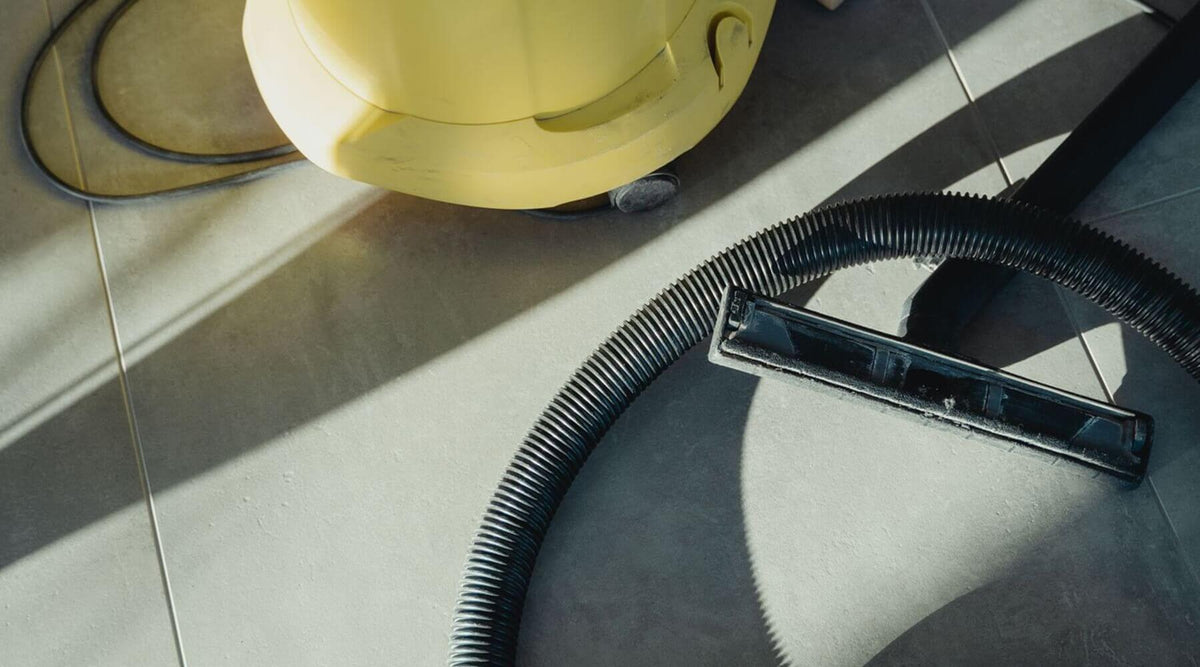 A vacuum cleaner on a tiled floor, illustrating how to clean and care for a sisal cat scratcher