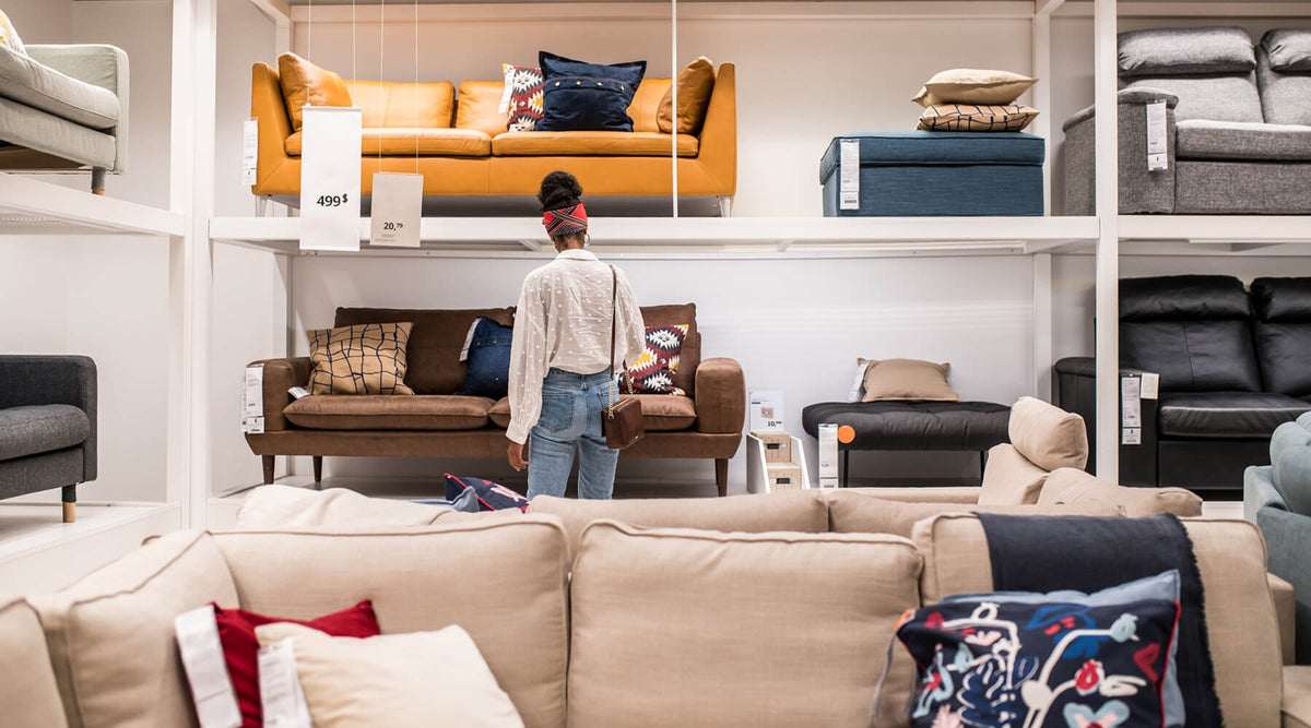 woman comparing couches in a furniture store before buying a sofa on Black Friday with cats